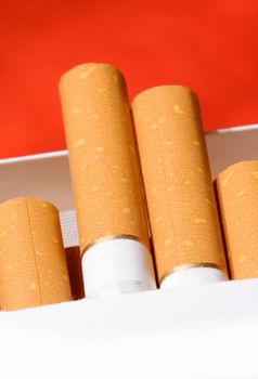 Pack of cigarettes on orange background. Shallow DOF