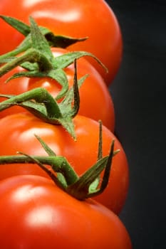 Row of fresh tasty tomatoes  on dark background