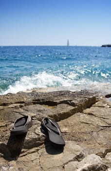 Gone swimming - flipflops on a rocky beach. Summer concept