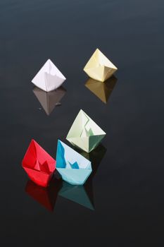 Set of motley paper boats on water background