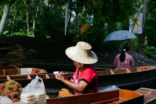 The seller by a boat. The seller of vegetables and fruit floats by a boat on the channel.