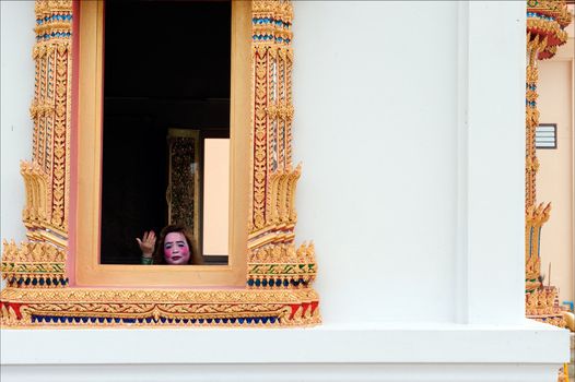 The invitation. The painted woman's face in a window of a Thai temple.