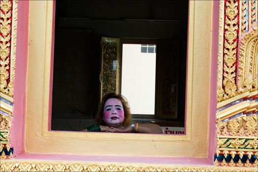  The painted woman's face in a window of a Thai temple.