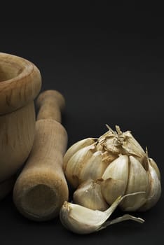 Garlic with mortar and pestle isolated on a black background.