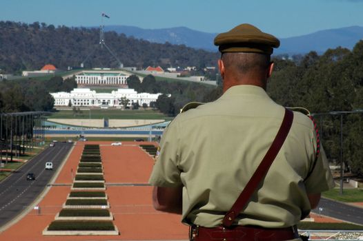australian soldier in foreground, blurred Canberra Parliament House in background
