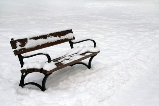 wooden bench in winter, clear snow on ground and on bench