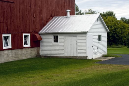 white milk house attached to a vintage red barn