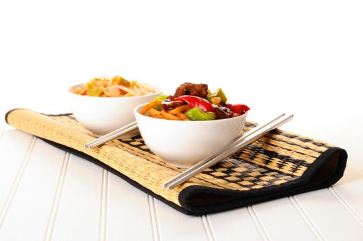 Bowls of delicious chinese food on a bamboo mat.