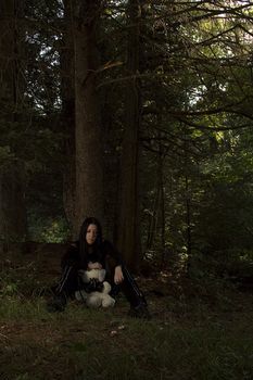 portrait of a twenty something girl dress in goth fashion with a white teddy bear wearing a gaz mask, while being scared lost in the woods