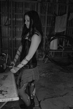 Twenty something women in goth style clothing sharpening axe