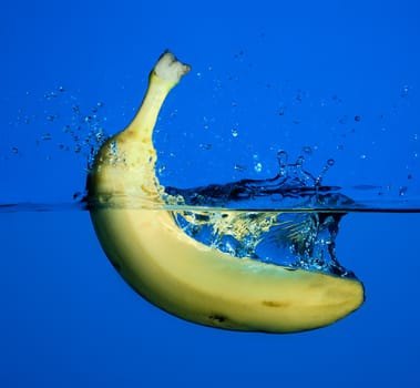 Banana splash on water, blue background.