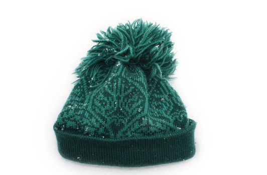Warm woolen hat on white background covered with snowflakes