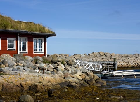 Red house by the sea, with a private harbour and boat.