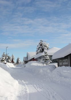 Narrow winter street between snow covered houses