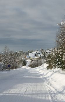 Snowy road leading to a village in a white winter landscape in western Norway.