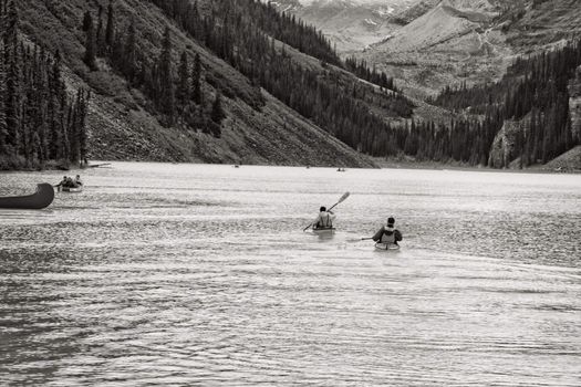 Paddling in a canoe on the beautiful turquoise colored Lake Louis against the backdrop of the majestic mountains of the Canadian Rockies partially covered with fog