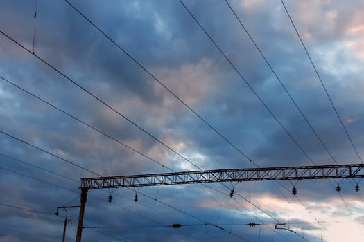 Power line of electric trains on the background of the cloudy sky at sunset