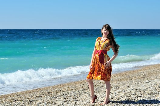longhaired pretty woman in orange on the beach 