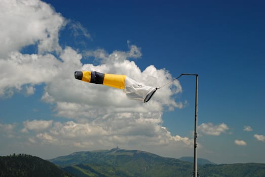 Wether-cock on Tete de Ran meteo station showing the wind dirrection, Jura hills and the sky is at background