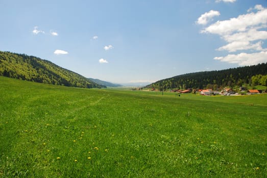 This is very large valley calling "Vallee de la Sagne et des Ponts" situating in Switzerland Jura, it is a grate field space with some farms and animal houses, green colours in spring time