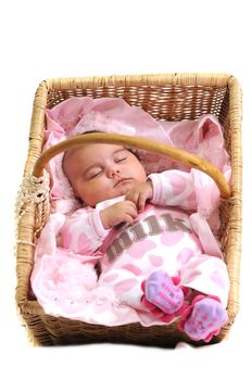 baby girl in pink dots laying in a brown basket draped with white beads