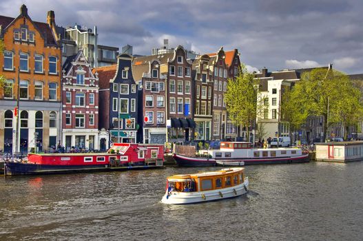 Classical Amsterdam view. Boat floats on the channel on the background of Dutch houses. Urban scene.