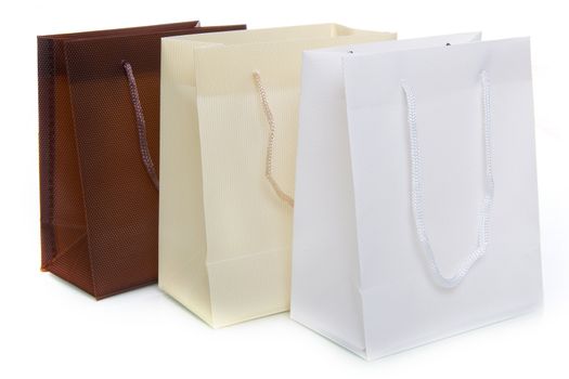three bags, a brown, a white and a creme one, on a white background