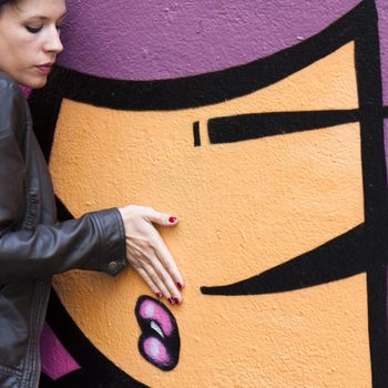 Girl putting her hand near a painted mouth