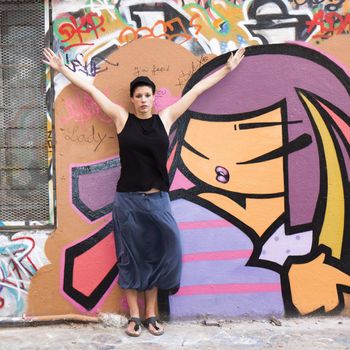 a young woman makes her gym before a wall covered