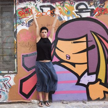 a woman stretches before a wall covered in graffiti