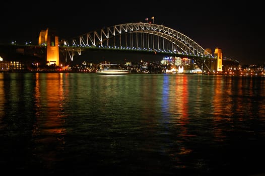 night scene of Harbour Bridge, lights reflected in water, boat in motion, photo taken from Opera House,