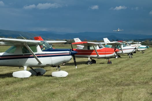 several aeroplanes on land, landing plane in background, air show