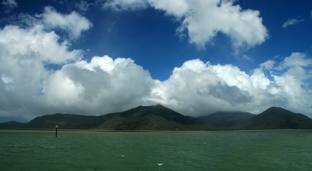 green ocean, green forest mountains, dark blue sky, clouds, ocean view