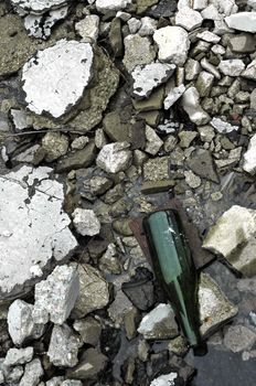 old green bottle between broken blocks of concrete