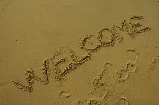 welcome written in sand on a beach