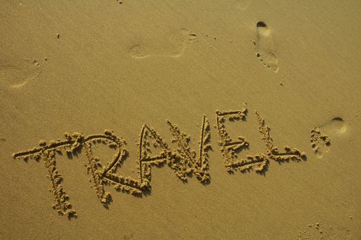 travel written in the sand on a beach