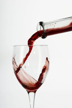 Flowing red wine from bottle to glass