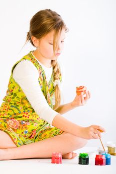 Studio portrait of a young blond girl painting eggs for easter