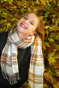 Portrait of a beautiful teenage girl in a fall park with fallen leaves