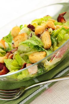 Caesar salad with croutons and bacon bits served in a glass bowl