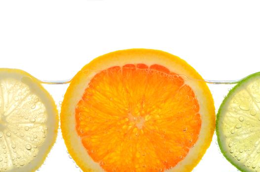 Orange lemon and lime slices in water with air bubbles on white background