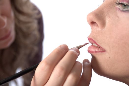 Studio image of make-up artist at work applying lipstick