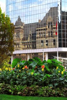 Reflection of old Toronto city hall building in a glass wall of a modern highrise 