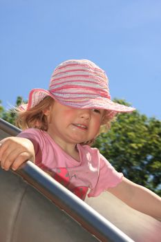 little girl with hat on a slide