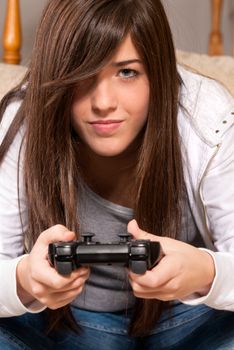 Young female concentrating playing videogames close-up on sofa at home