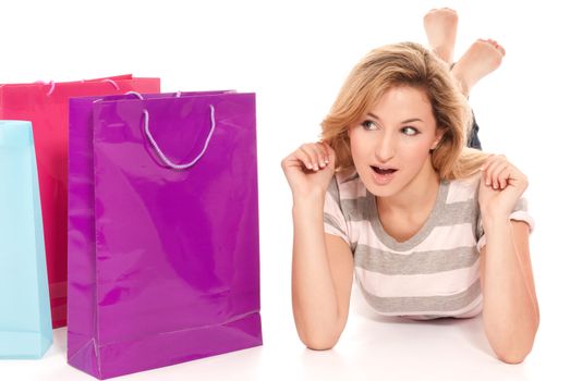 Young woman with shopping bags lying on floor on white background