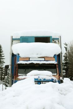 Old derelict blue truck covered in snow