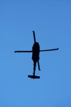 A helicopter silhouette aginst blue sky
