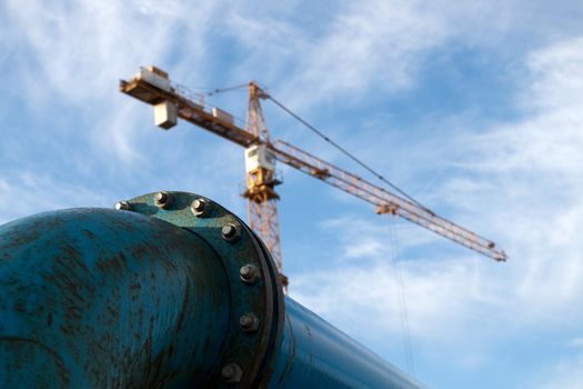 Blue pipelines with bolts at construction site with crane in background