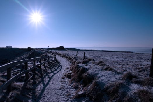 frosty winters view at ballybunion cliffside walk with bright sun and fence